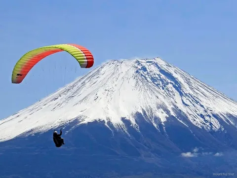 Tandem paragliding pilot and flyer with Mount Fuji in view